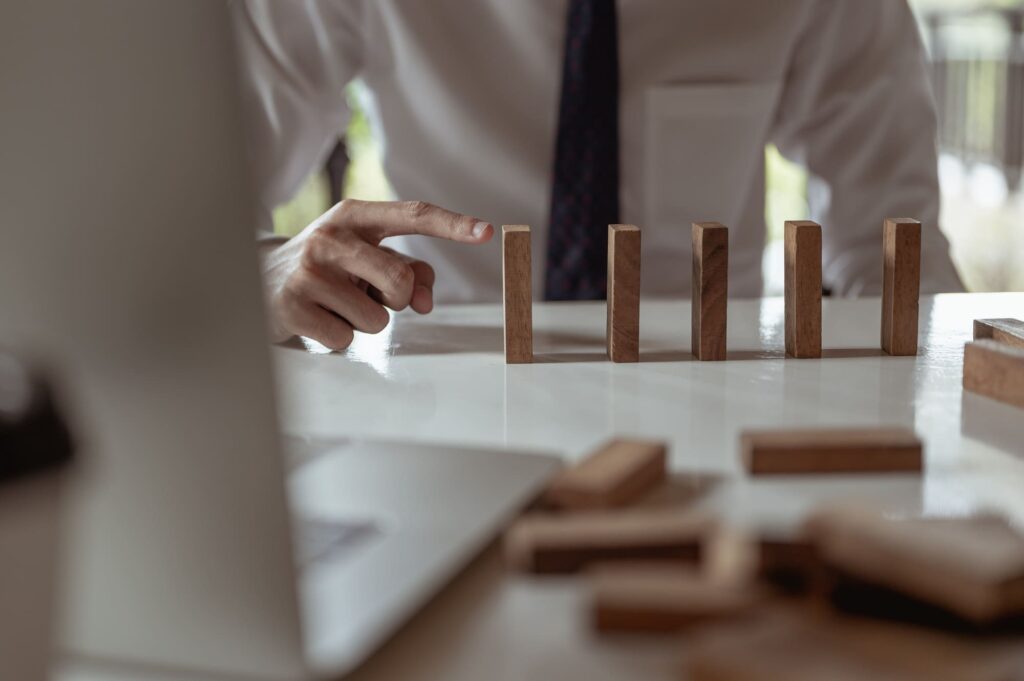 Businessman pulling or placing long wooden blocks in a modern office Indicates the impact