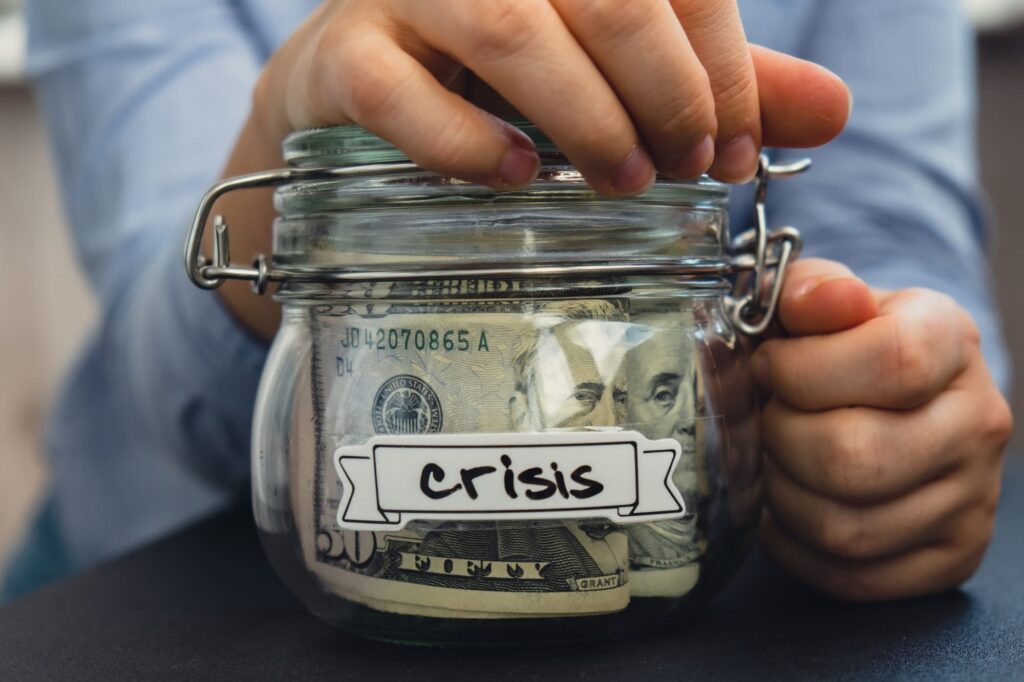 Unrecognizable woman holding Saving Money In Glass Jar filled with Dollars banknotes. CRISIS