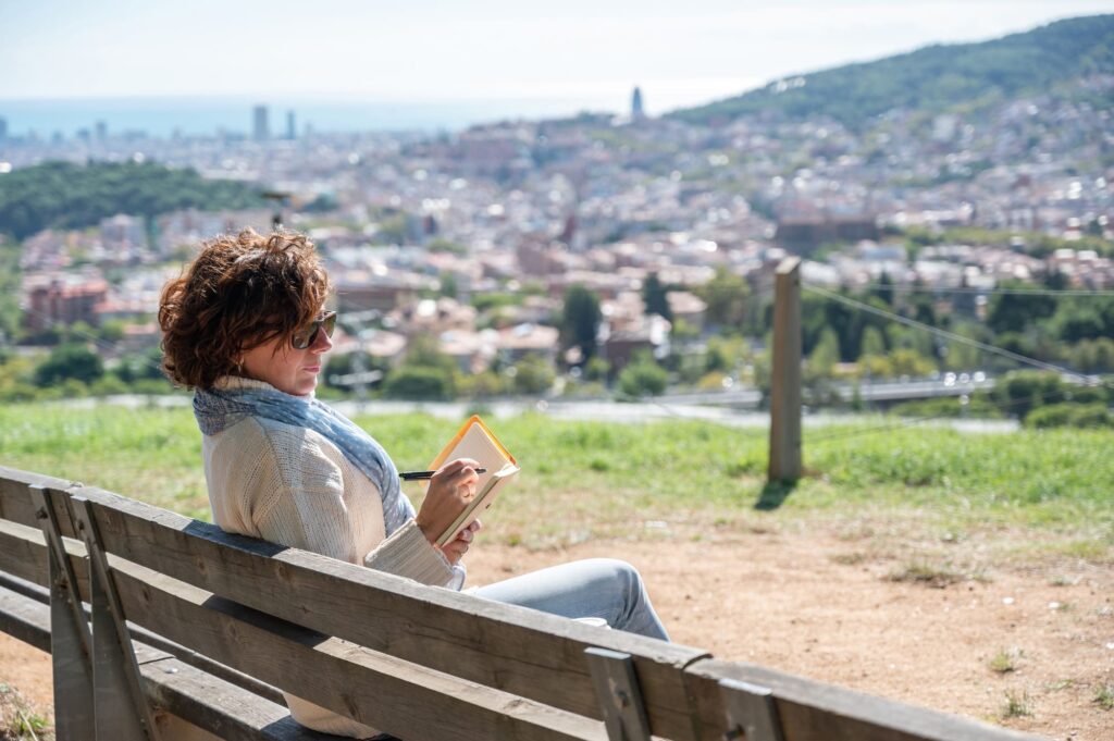 Writer creating new story sitting on bench overlooking barcelona cityscape