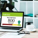 cup of coffee near laptop with credit score lettering and numbers on screen