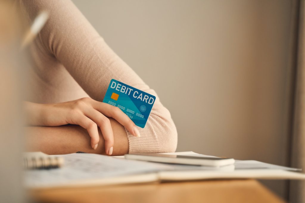 Woman in a sweater holding a debit card