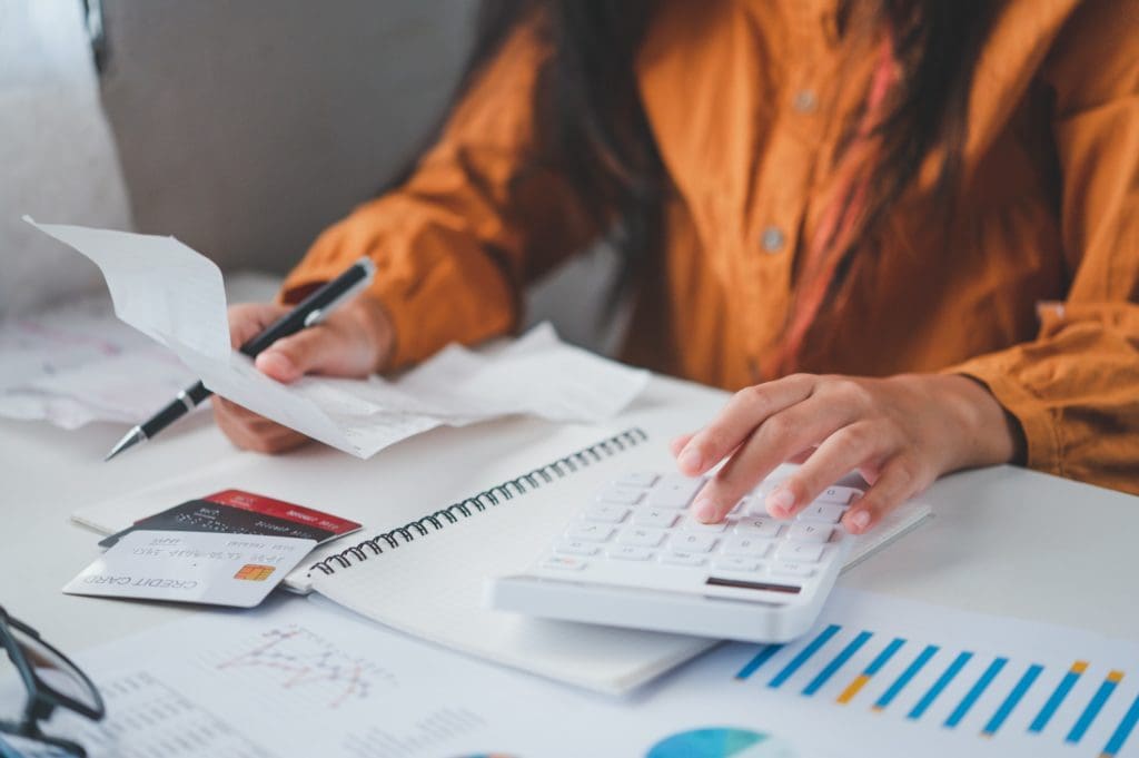 business person sitting at a desk at an office By using the calculator to work.