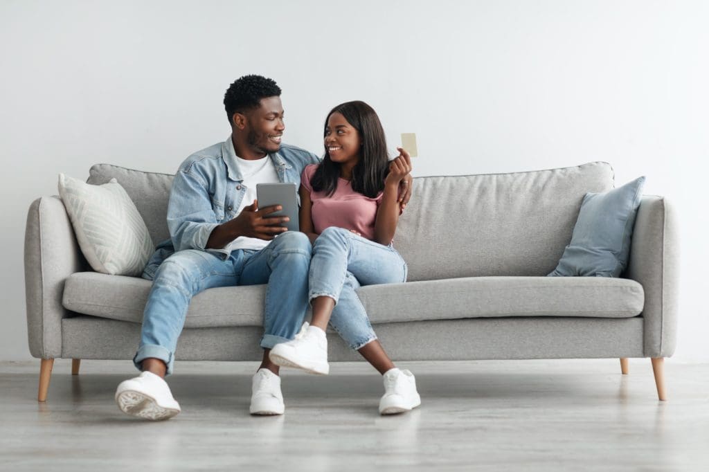 Black couple using tablet and credit card at home