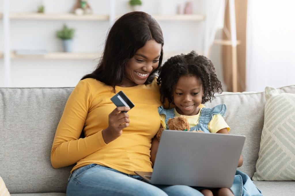 Happy Black Mother And Daughter Shopping Online With Computer And Credit Card