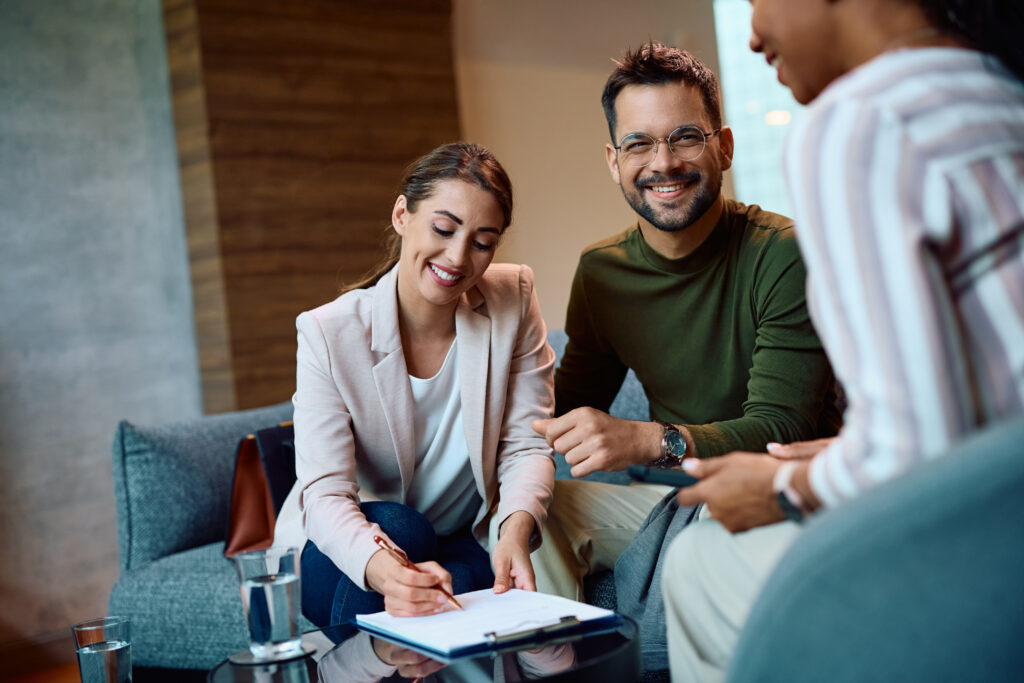 Young couple signing a contract while having meeting with insurance agent in the office.