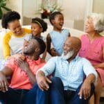 African american three generation family smiling looking at each other sitting on couch at home